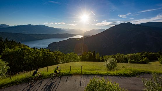 zwei Radfahrer auf erhöhter Straße über See