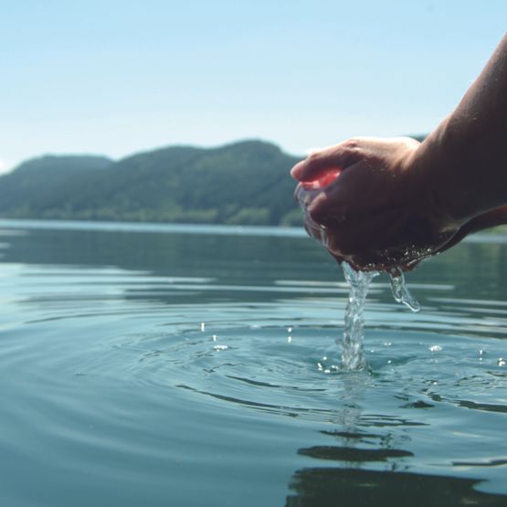 Hände schöpfen Wasser aus See