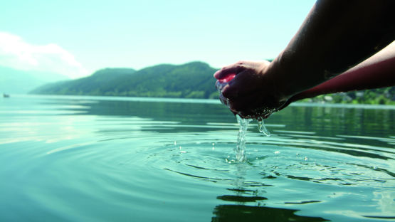 Hände schöpfen Wasser aus See